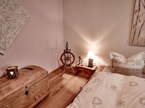 A bedroom with a wooden dresser, a spinning wheel, a small lamp, and a bed with a patterned blanket. - Cresta 5 Appartement/Fewo, Dusche oder Bad, WC 4 1/2-Zimmerwohnung by Interhome (Klosters)