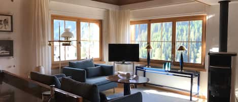 Amplia sala de estar con una televisión de pantalla plana grande, un sofá, una mesa de centro y una chimenea.