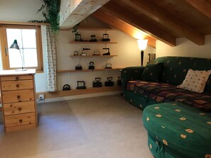 A cozy room with a wooden dresser, a green sofa with patterned cushions, and shelves with various kitchen utensils. - Gufer - Maisonett Appartement/Fewo, Dusche oder Bad, WC 3½-Zimmerwohnung by Interhome (Davos)