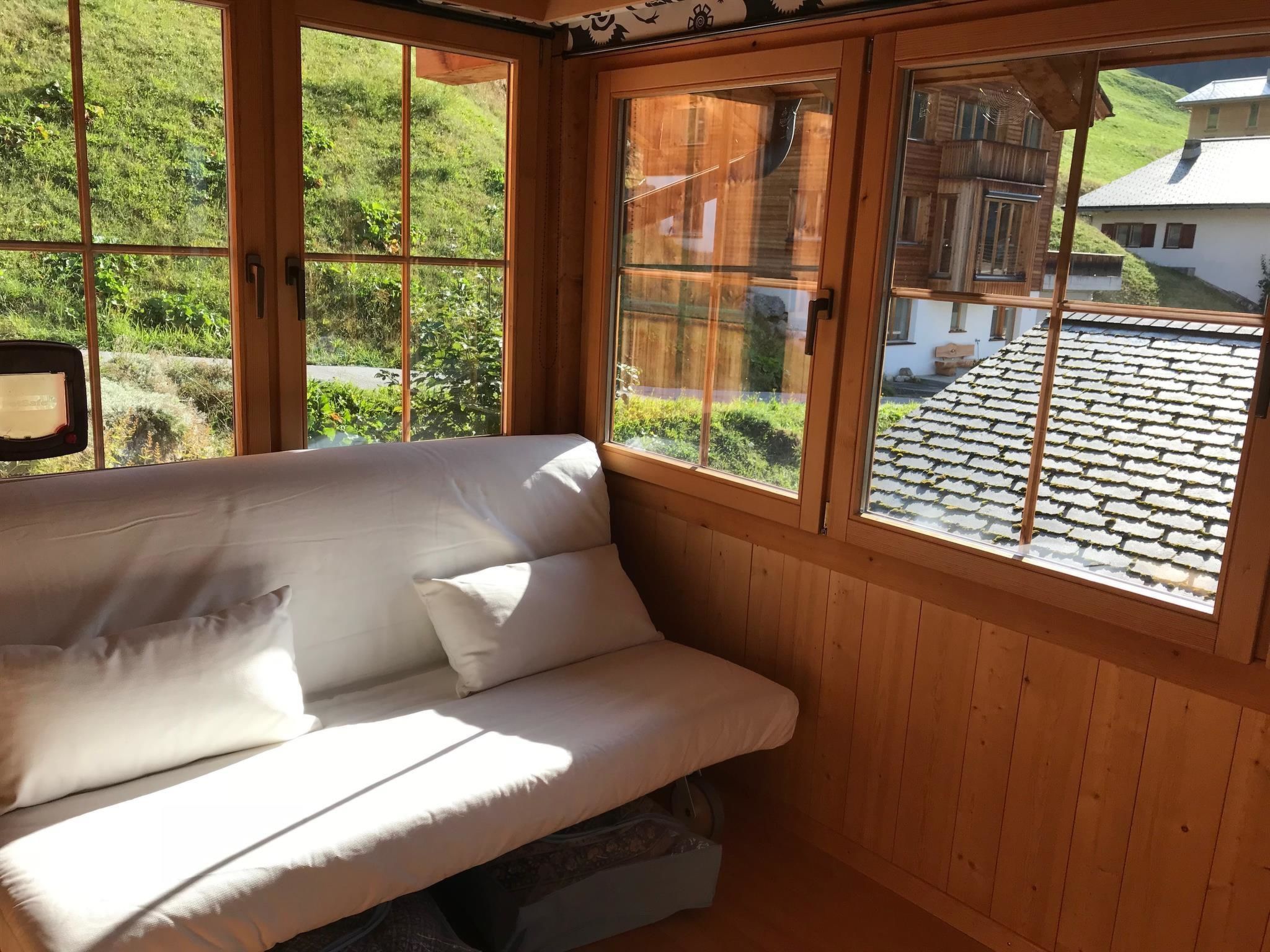 A wooden room with a white sofa and large windows.