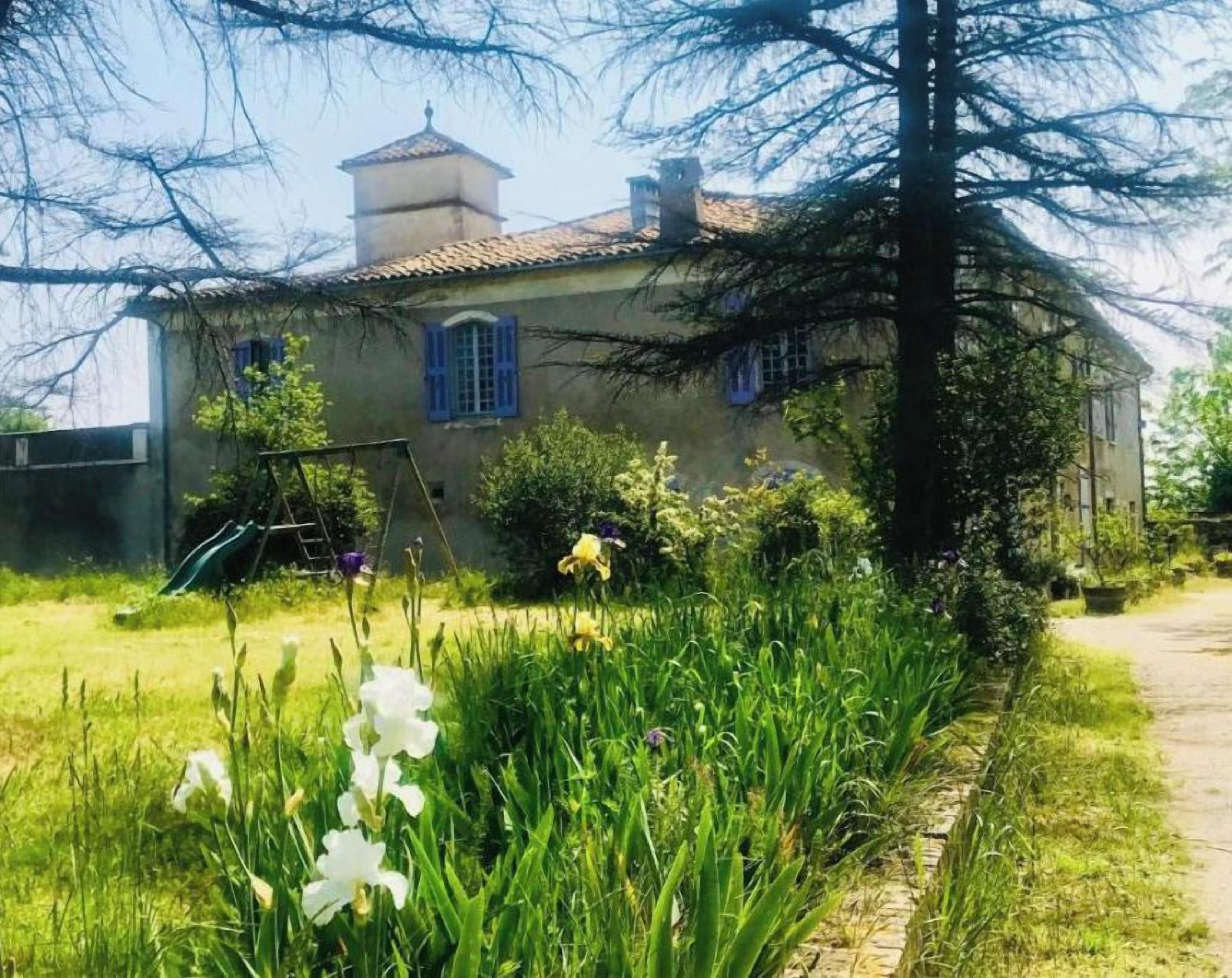 Une maison avec un jardin, une balançoire et un ciel dégagé.
