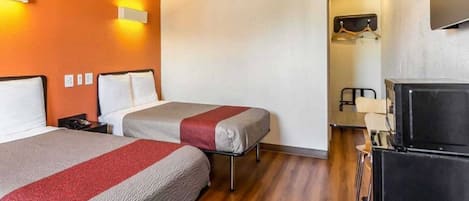 Habitación de hotel con dos camas, un televisor y un escritorio con una silla.