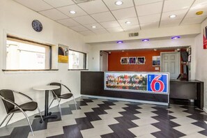Un hall d’hôtel comprenant un comptoir d’enregistrement, un espace détente avec deux fauteuils et un sol à motifs.