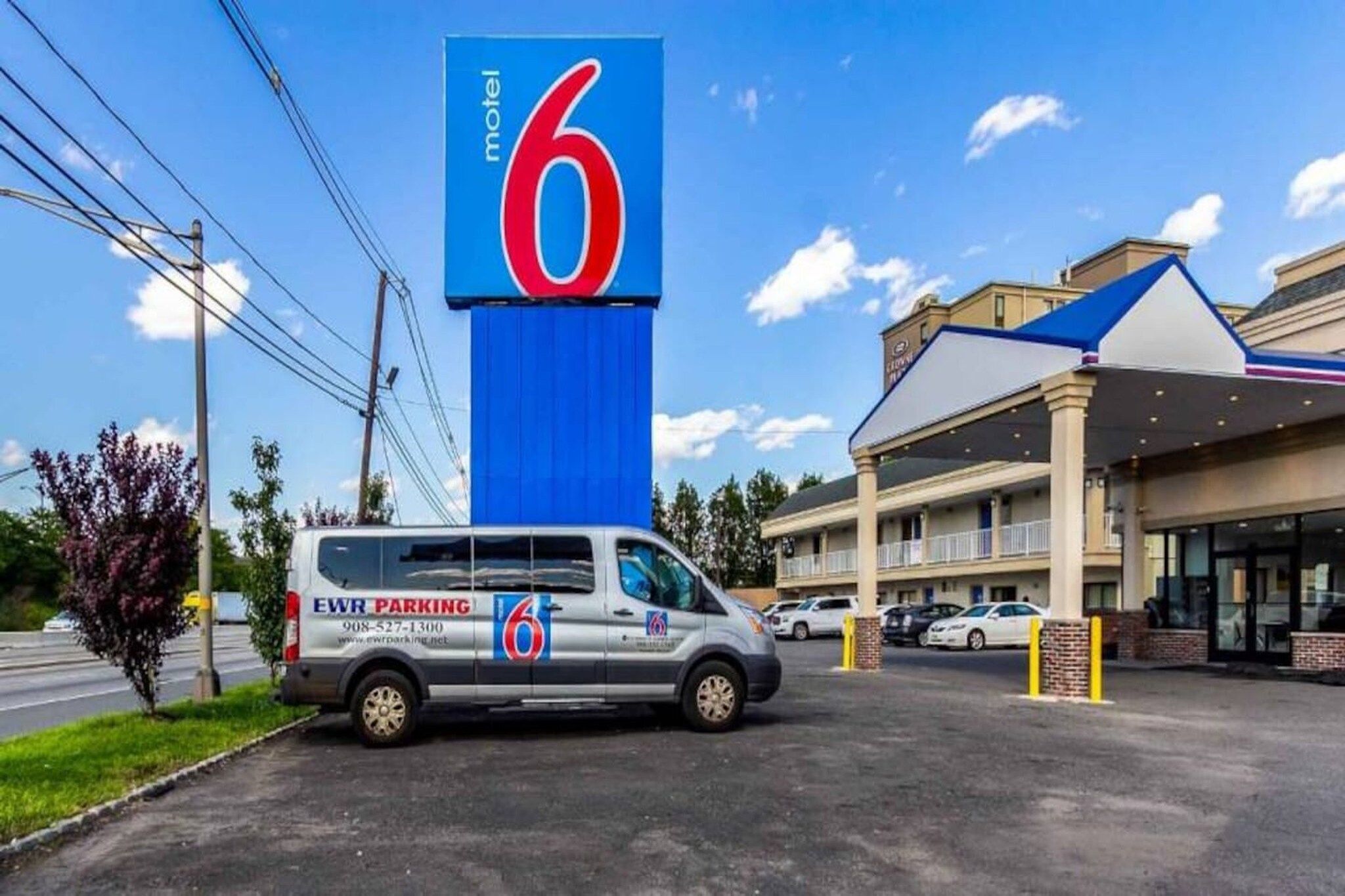 A motel with a prominent '6' sign, a parking area, and a building with a blue roof.