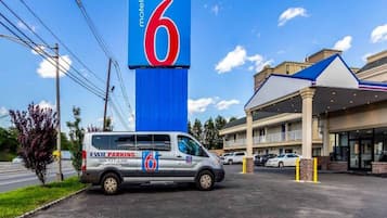 A motel with a prominent '6' sign, a parking area, and a building with a blue roof.