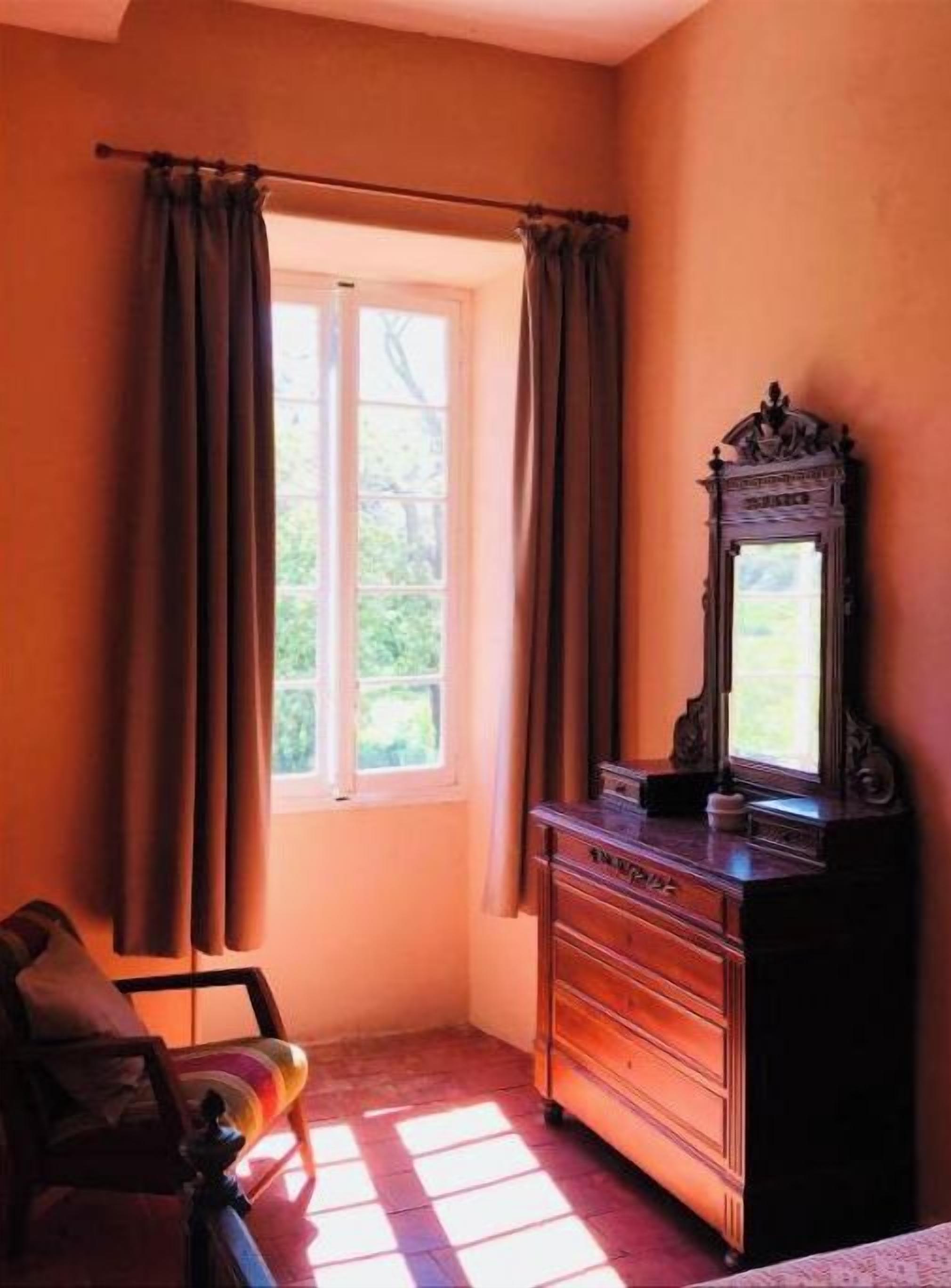 Ein Zimmer mit Fenster, Kommode und Stuhl.