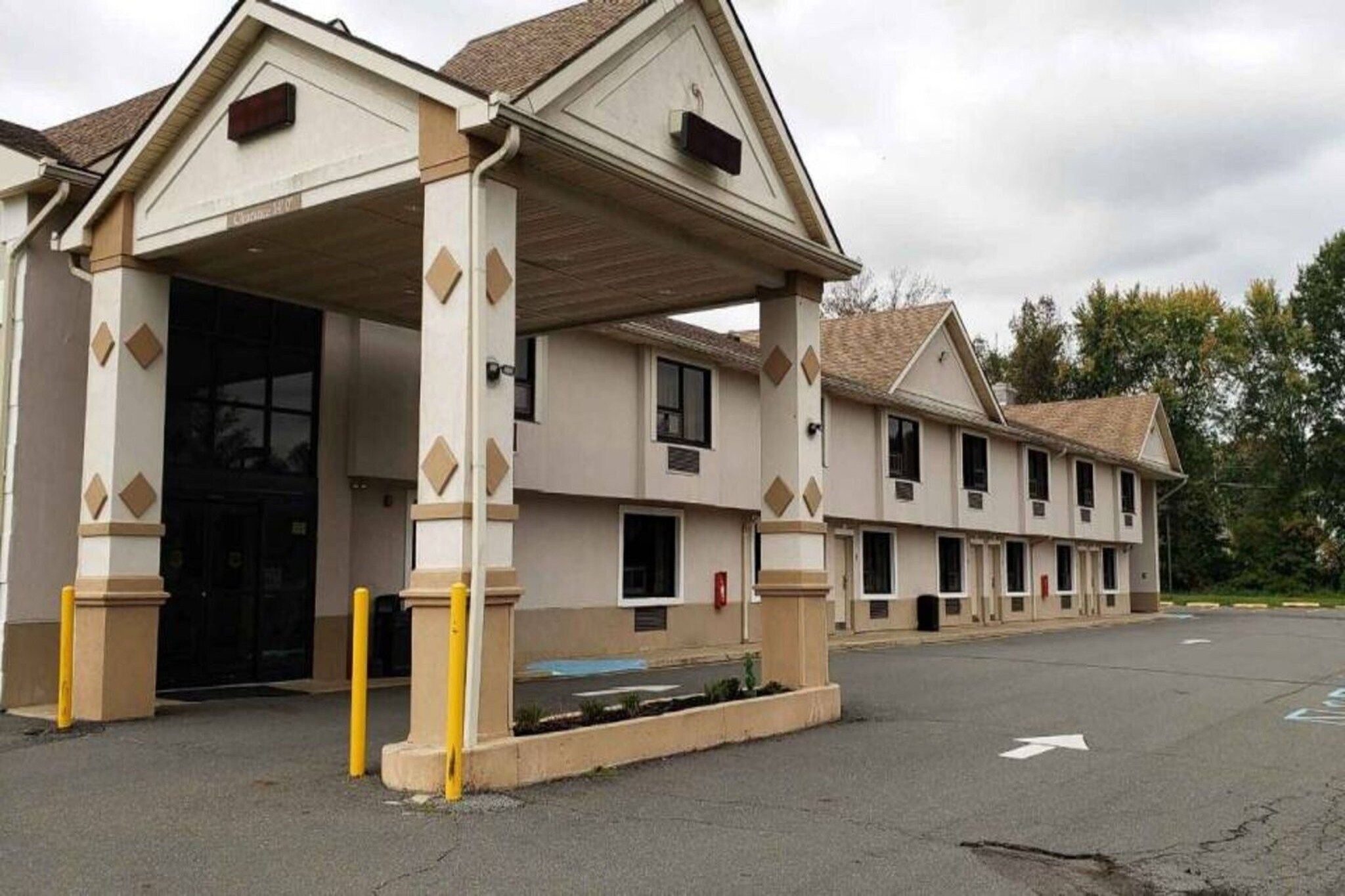 Un motel con ingresso coperto, diverse finestre e un parcheggio.
