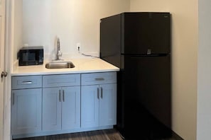 A compact kitchen with a sink, a microwave, and a black refrigerator. - Cozy King Bed|Free Parking & Wifi (East Windsor)