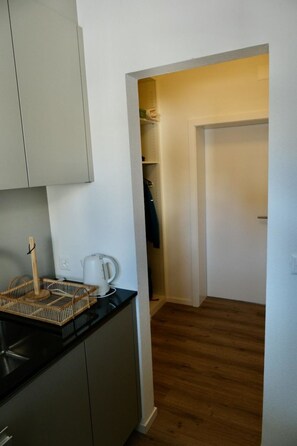 A compact kitchen with a kettle, a basket, and a wooden floor. - M Köhler Appartement/Fewo, Dusche oder Bad, WC 1-Zimmerwohnung by Interhome (Davos)