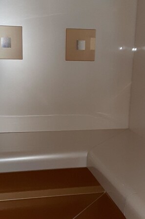 A room with a white wall, a brown floor, and two square light fixtures. - Residenz Meierhof 251 Appartement/Fewo, Dusche oder Bad, WC 2 1/2-Zimmerwohnung by Interhome (Davos)