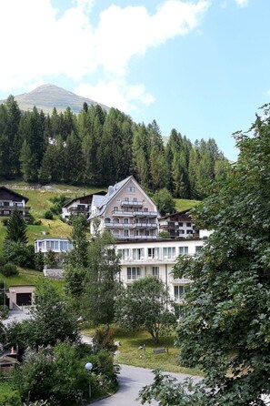 A hotel with multiple balconies, surrounded by lush greenery and a mountain in the background. - Residenz Meierhof 251 Appartement/Fewo, Dusche oder Bad, WC 2 1/2-Zimmerwohnung by Interhome (Davos)