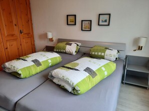 A double bed with a grey mattress and two pillows, a wooden door, and two wall-mounted lamps. - Residenz Meierhof 251 Appartement/Fewo, Dusche oder Bad, WC 2 1/2-Zimmerwohnung by Interhome (Davos)