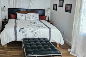 A bedroom with a bed, bedside tables, a bench, and framed pictures on the wall. - 6 Mi to Beach! Sarasota Studio w/ Screened Porch (Sarasota)