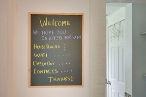 Een schoolbord met een welkomstboodschap en een opsomming van huisregels.