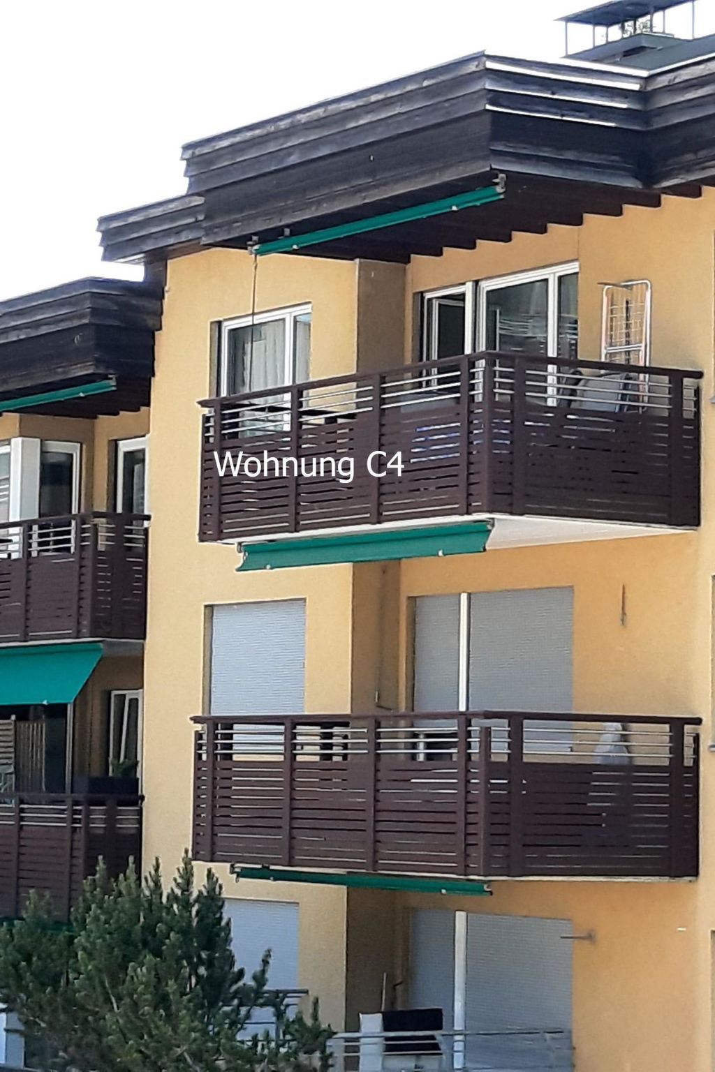 A multi-story residential building with balconies and a green awning.