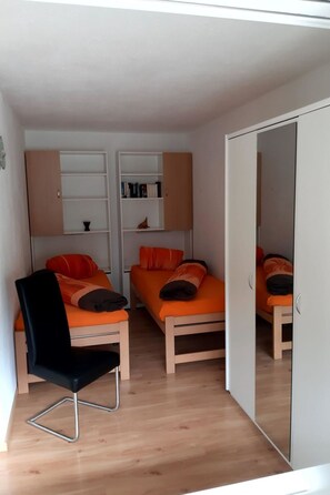 Een knus slaapkamer met twee bedden, een stoel en een kledingkast.