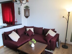 A living room with a dark-colored sofa, a wooden coffee table, and a floor lamp. - Carlton am Golf C46 Appartement/Fewo, Dusche oder Bad, WC 2-Zimmerwohnung by Interhome (Davos)