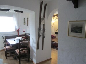 A dining area with a table and chairs, a wall-mounted clock, and a framed picture. - Carlton am Golf C46 Appartement/Fewo, Dusche oder Bad, WC 2-Zimmerwohnung by Interhome (Davos)
