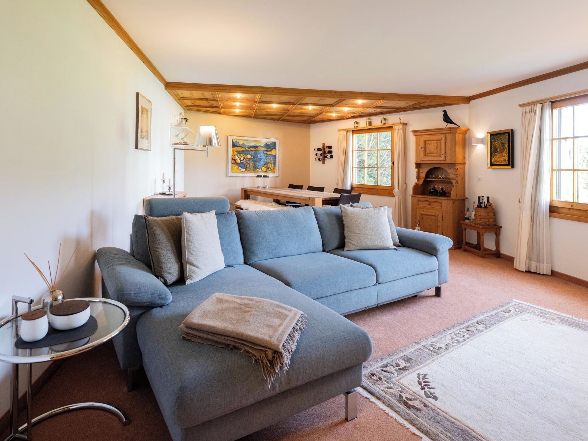 Ein modernes Wohnzimmer mit einem blauen Sofa, einem Esstisch und einer Küchenzeile.