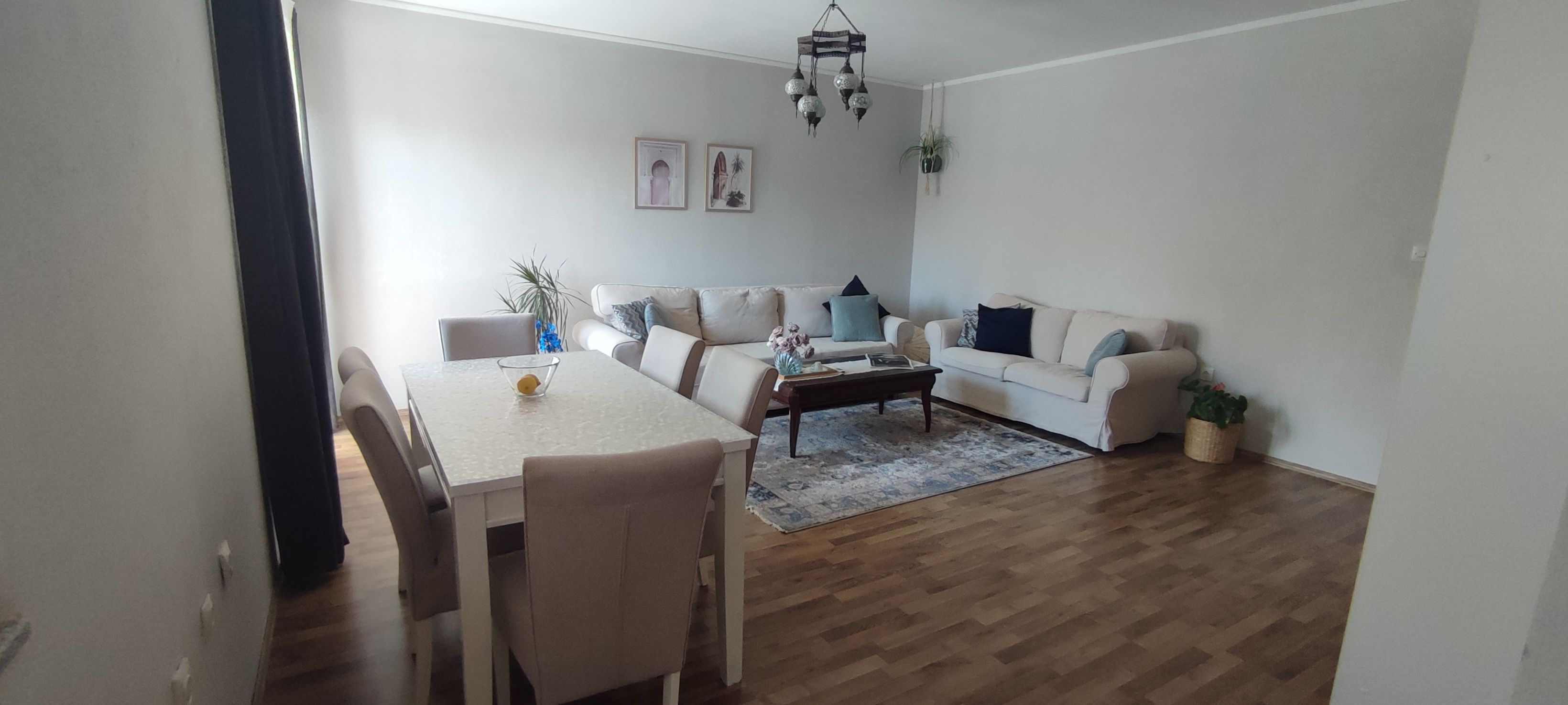 Ein Wohnzimmer mit Esstisch, zwei Sofas, einem Couchtisch und einer Kandelaber.