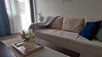 Ett vardagsrum med en soffa, ett soffbord och en prydnadsväxt.