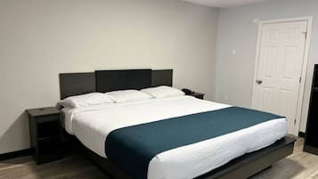 A standard hotel room with a single bed, a bedside table, a nightstand, and a door.