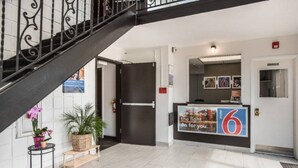 Un hall d’hôtel avec un escalier, un comptoir d’accueil et une porte.