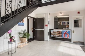 Un vestíbulo de hotel con una escalera, un mostrador de recepción y una puerta.