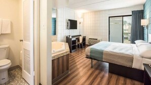 Une chambre d’hôtel comprenant un lit, un bureau, une chaise, une télévision et une salle de bain.