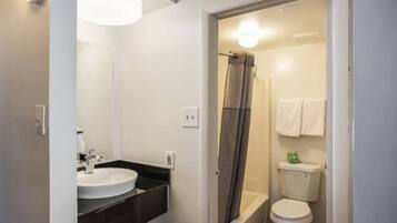 A bathroom with a sink, mirror, shower curtain, and toilet.