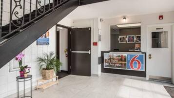 Zona de recepción de un hotel con una escalera, un mostrador de recepción y una puerta.