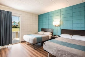 Habitació d'hotel amb dos llits, un balcó i vista a una casa.