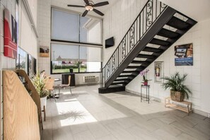 A spacious interior with a staircase, large windows, and a view of the outside. - Spacious 2 Queen Beds | Non-Smoking (Somers Point)