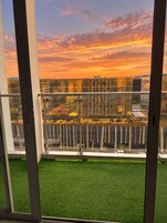Blick von einem Balkon mit künstlichem Rasen auf eine Baustelle mit Metallkonstruktionen und Gerüsten.