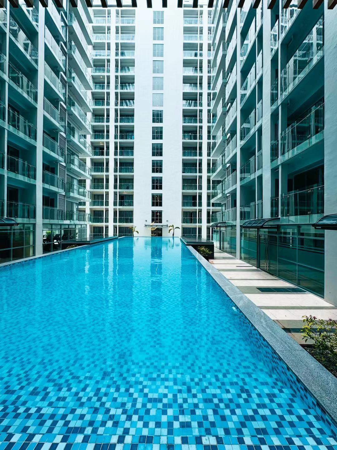 A modern building with a central swimming pool surrounded by multiple floors of balconies.