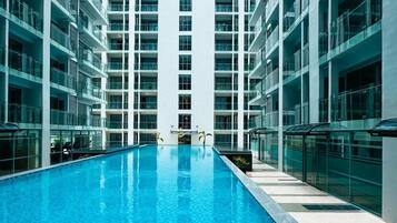A modern building with a central swimming pool surrounded by multiple floors of balconies.