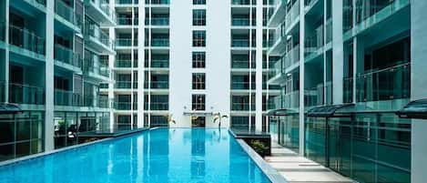 Un edificio moderno con una piscina central rodeada por varios pisos de balcones.