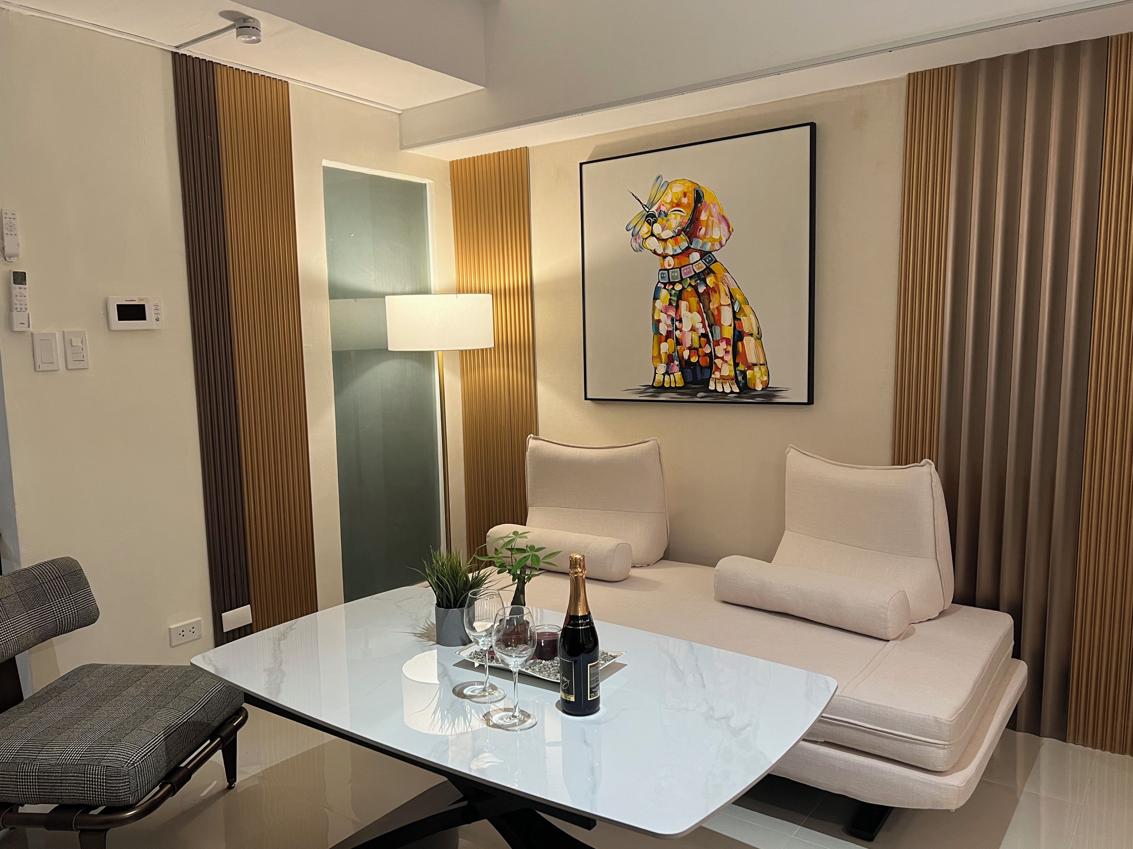 A modern living room with a white sofa, a glass coffee table, and a colorful abstract painting.