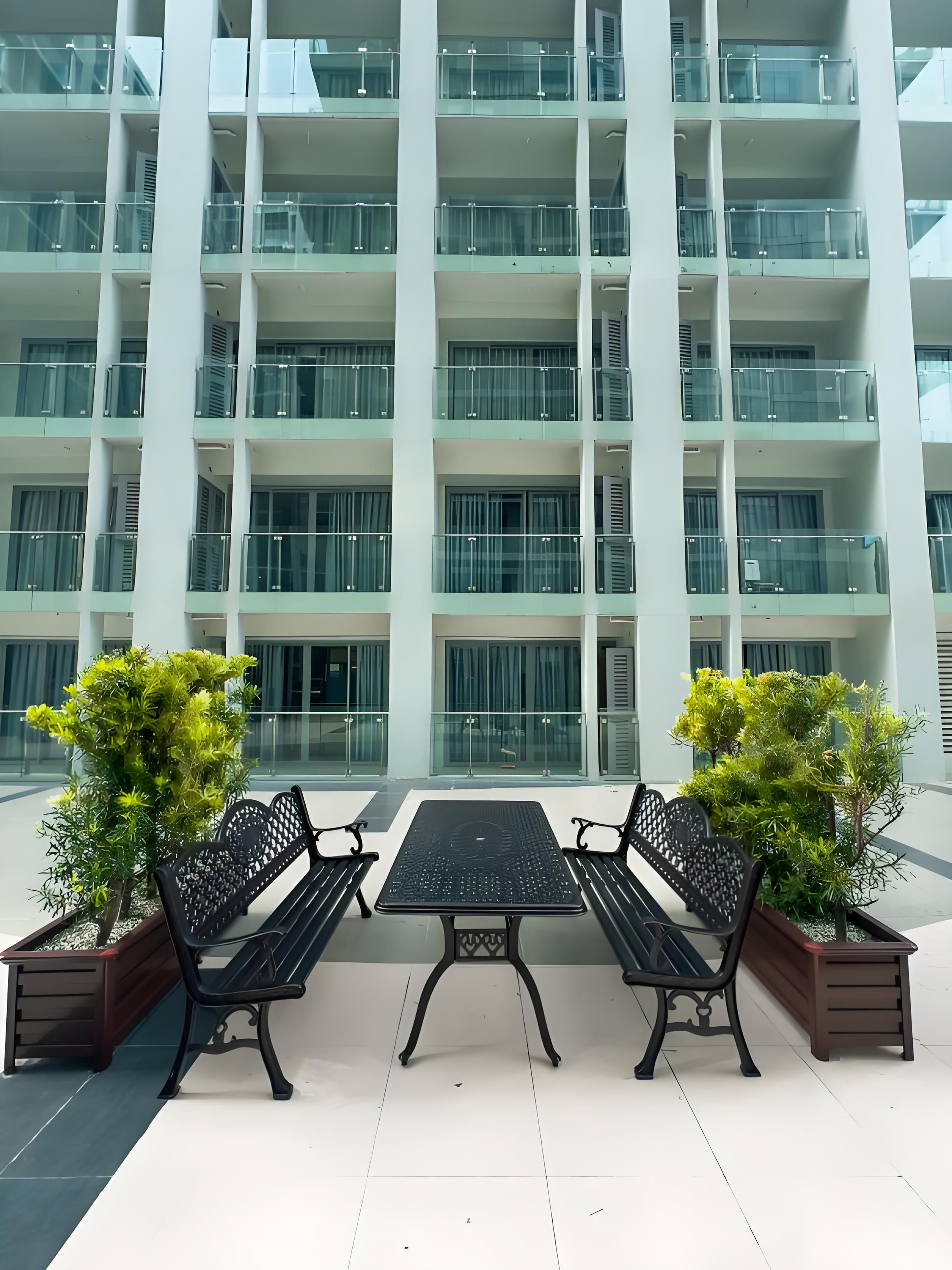 A modern building with multiple balconies and a seating area with two benches and a table.