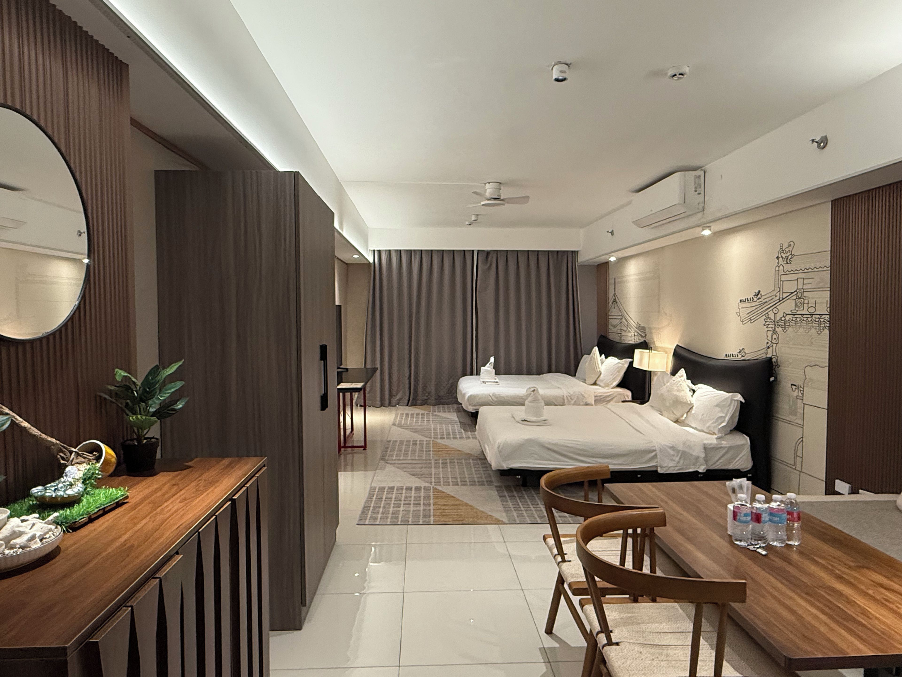 Una habitación de hotel con una cama, mesitas de noche, un escritorio, sillas y una mesa de comedor.