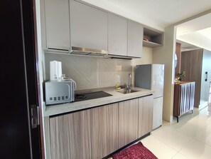 A modern kitchen with a built-in microwave, toaster, sink, and stainless steel refrigerator. - Modern Cozy Sunlit Apt Next to AirportS (ParaƱaque)