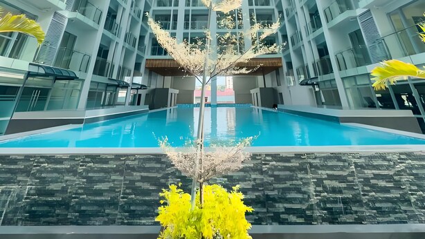A high-rise building with a central atrium and a swimming pool at the base. - Modern Cozy Sunlit Apt Next to AirportS (Parañaque)