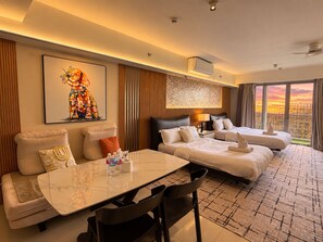Ein Hotelzimmer mit Bett, einer Couch, einem Esstisch und Blick auf die Stadtlandschaft.