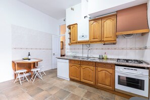 Eine kompakte Küche mit Holzschränken, einem eingebauten Backofen und einer kleinen Essecke mit Tisch und Stühlen.