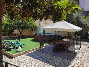 Eine Terrassenanlage mit Billardtisch, Sitzgelegenheiten im Freien und einem überdachten Bereich.