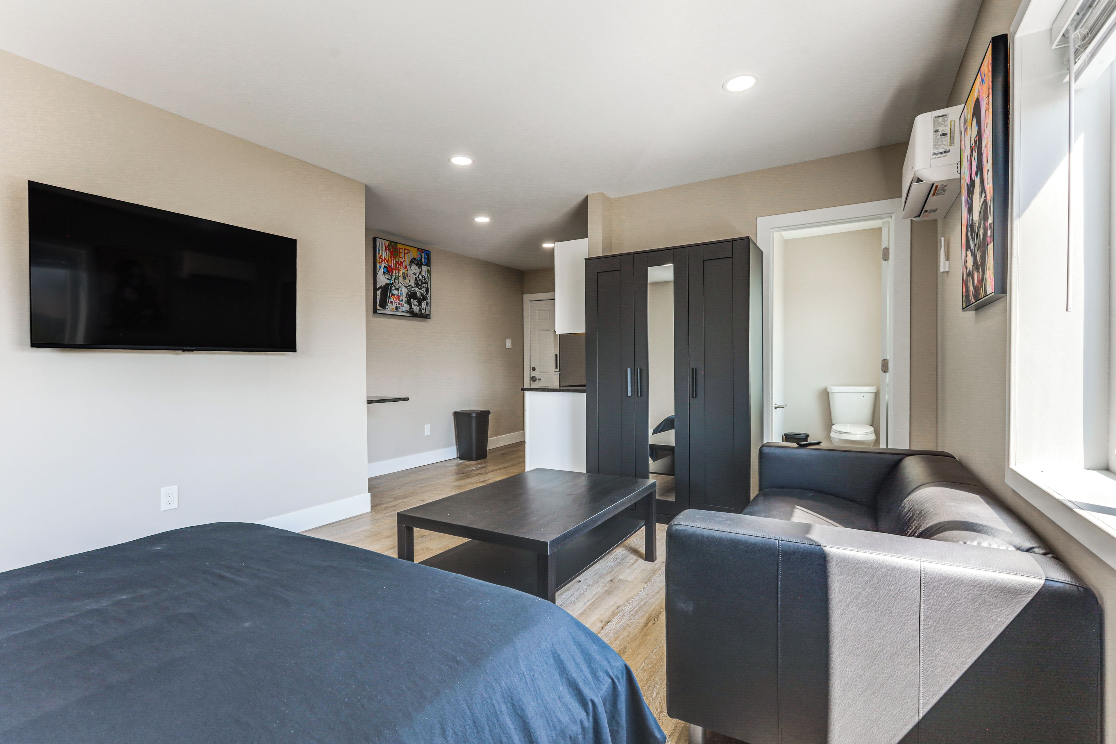 Une chambre d’hôtel moderne équipée d’une télévision à écran plat, d’un canapé, d’une table et d’une armoire.
