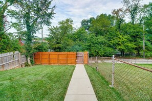 Ein Garten mit Holzzaun, Betonweg und Maschendrahtzaun.
