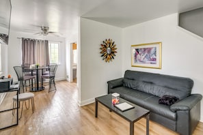 Ein modernes Wohnzimmer mit grauem Sofa, einem Couchtisch und einem Essbereich mit Stühlen und Tisch.