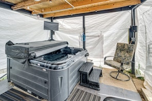 Ein Whirlpool mit Fernseher, einem Sessel und einem überdachten Bereich.