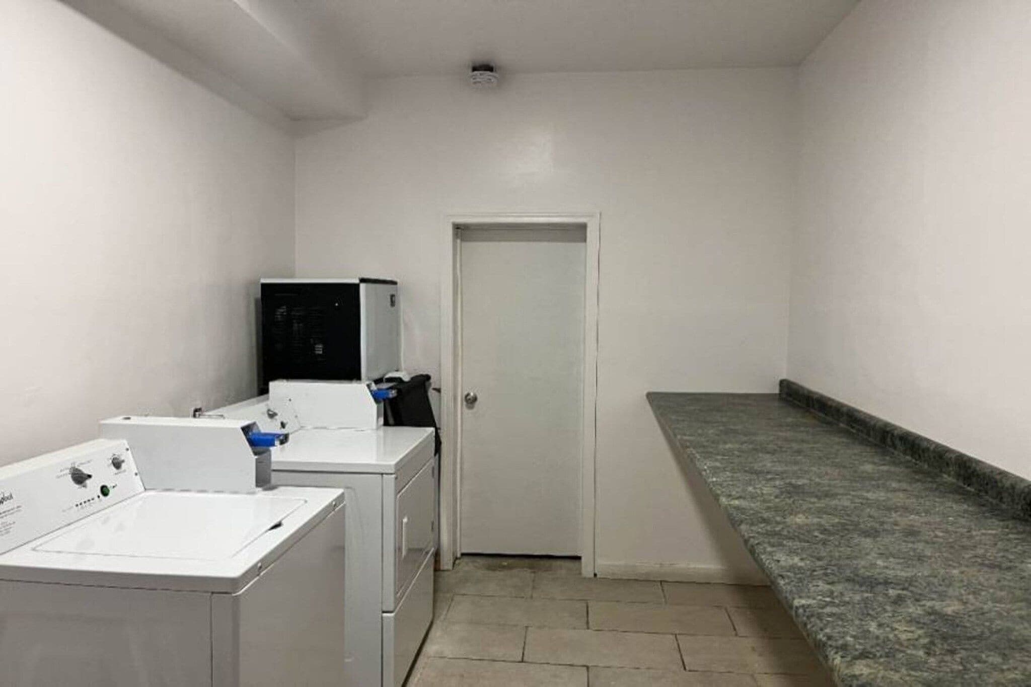 Un lavadero con lavadora, secadora y un refrigerador pequeño.